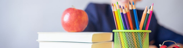 © Pexels, von Alexandr Podvalny Auf einem Tisch liegt ein Bücherstapel, auf dem ein roter Apfel liegt. Rechs daneben ist ein Stiftehalter mit Buntstiften in verschiedenen Farben zu sehen.